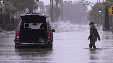 Rains from Tropical Storm Hilary swamp roads, trap cars and flood buildings